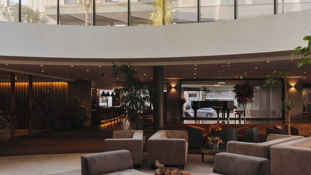 A spacious lobby with modern furniture, a central coffee table, and a view of a high-rise building with large windows. - Timbre Heroismo (Porto)