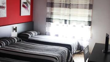 Una camera da letto con due letti, una scrivania e un televisore.