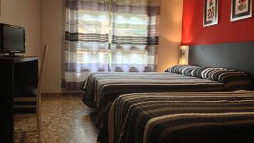 A bedroom with two beds, a desk, and a television.