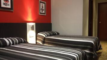 Een hotelkamer met twee bedden, een rode muur en twee ingekaderde foto's.
