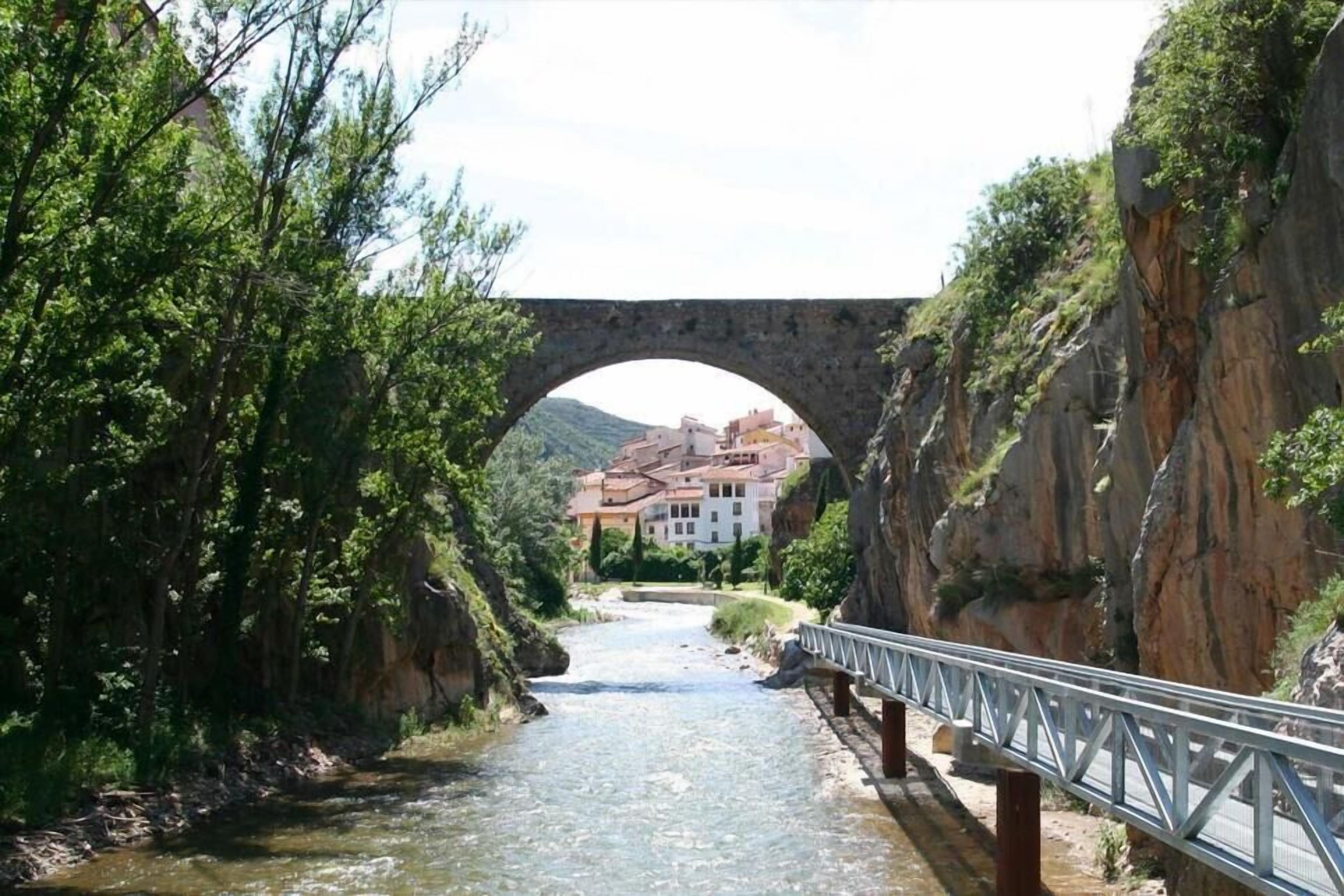 Un pont de pierre enjambant une rivière, avec un bâtiment visible au loin.