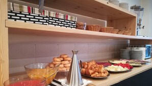 A buffet setup with various food items, including pastries, fruits, and a beverage dispenser. - Hotel Marrodan (Arnedillo)