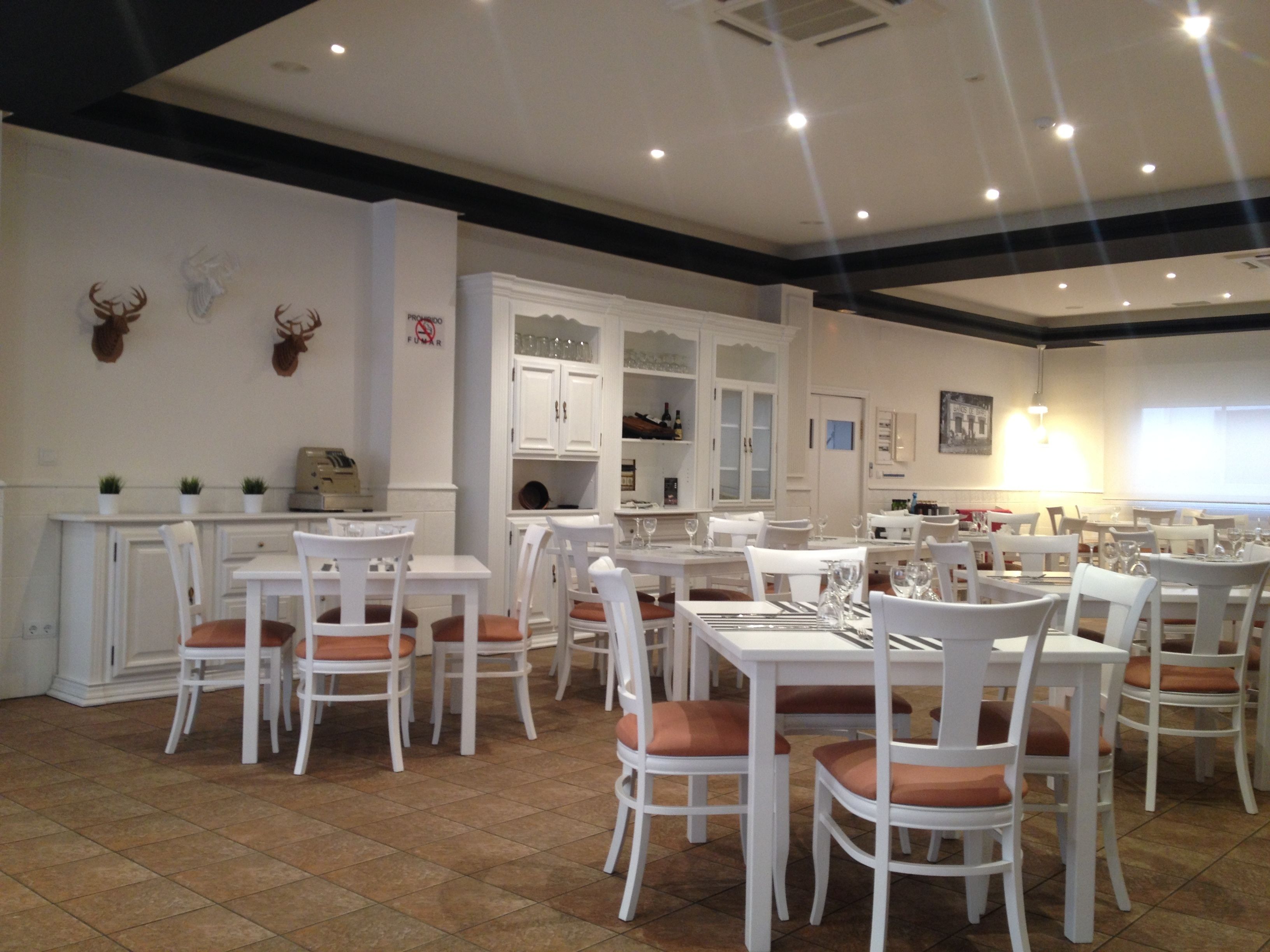 Un restaurant amb taules i caires blanques, un paviment de rajoles i un sostre amb il·luminació empotrada.
