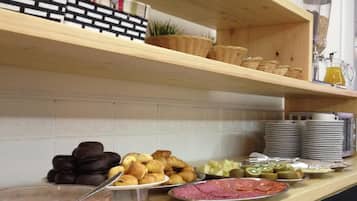 A buffet setup with various food items including pastries, fruits, and a bowl of soup.