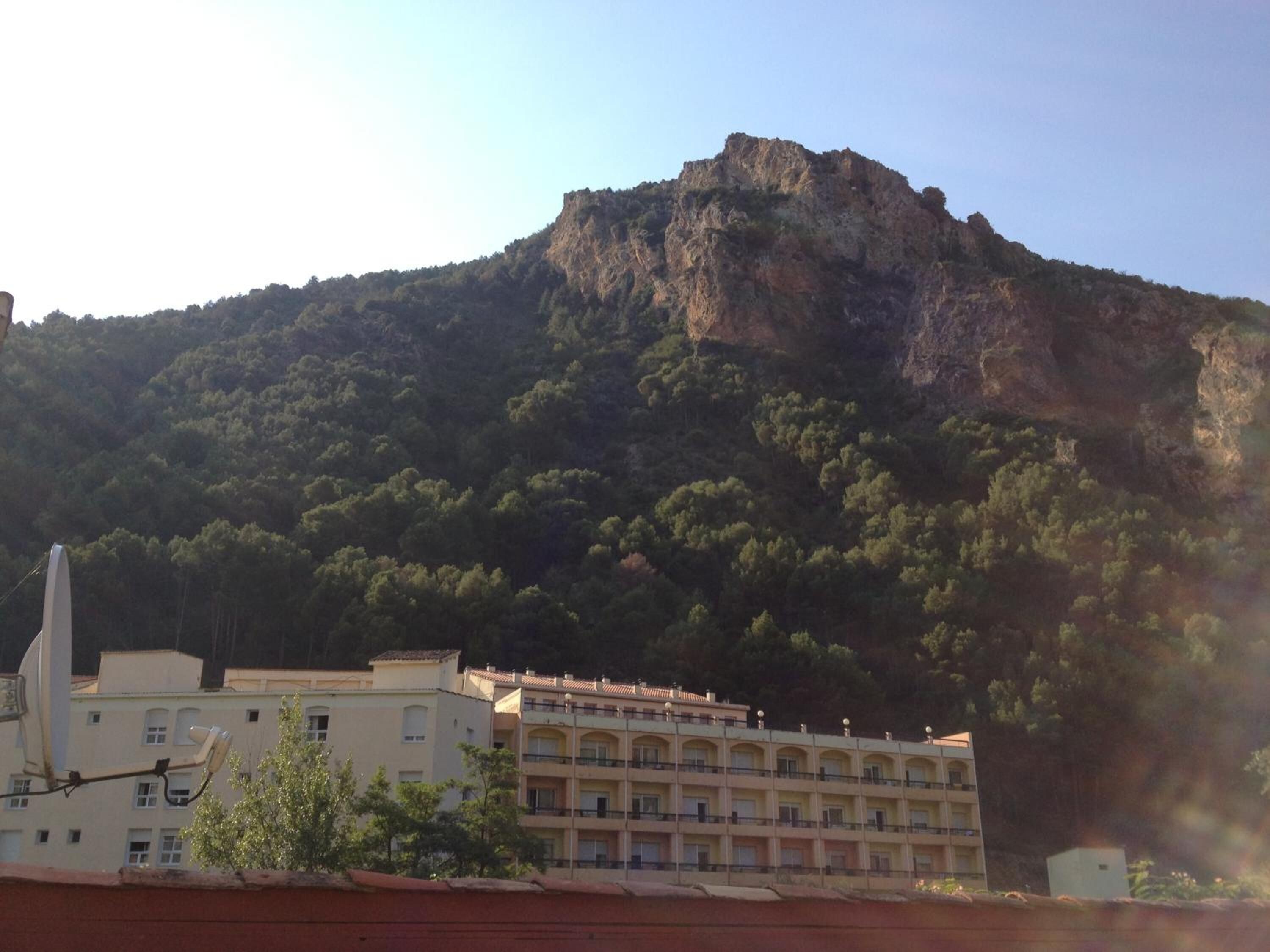 Un edificio con varios balcones y una montaña al fondo.