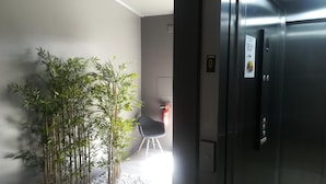 A modern interior with a bamboo plant arrangement, a chair, and a door to an elevator. - Hotel Marrodan (Arnedillo)
