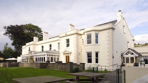 A large, white building with a stone wall, a covered patio, and picnic tables. - Premier Inn Merthyr Tydfil (Merthyr Tydfil)