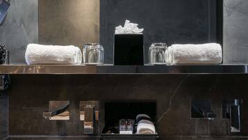 A bathroom with a dark marble countertop, two white towels, a glass jar, and a bottle of lotion.