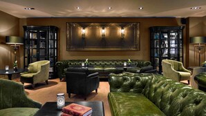 A luxurious living room with a green leather sofa, matching armchairs, a black coffee table, and a large framed artwork above the sofa. - La Cour des Consuls Hotel & Spa Toulouse - MGallery Collection (Toulouse)