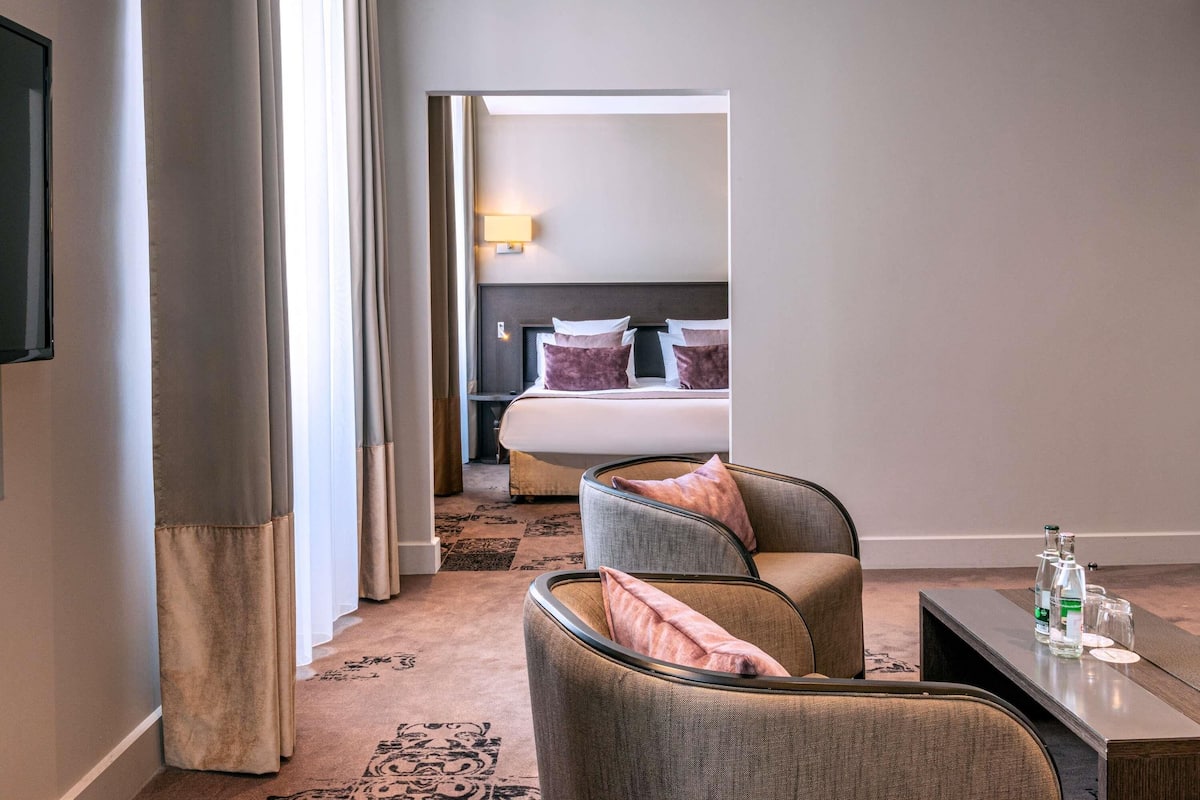 Ein Hotelzimmer mit einem Bett, einer Sitzecke mit Tisch und einem Fernseher.