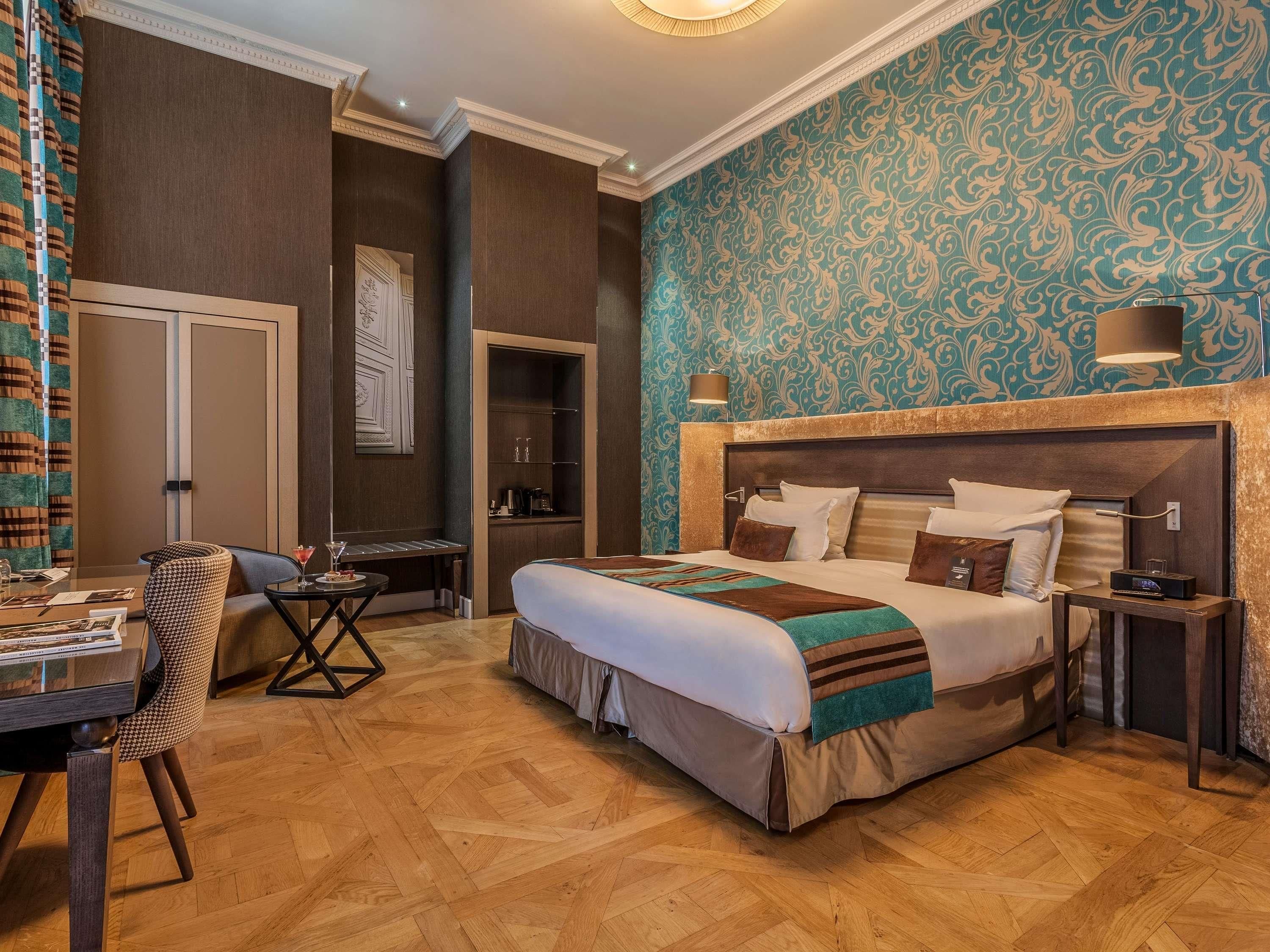 A hotel room with a bed, bedside tables, a desk, and a chair.