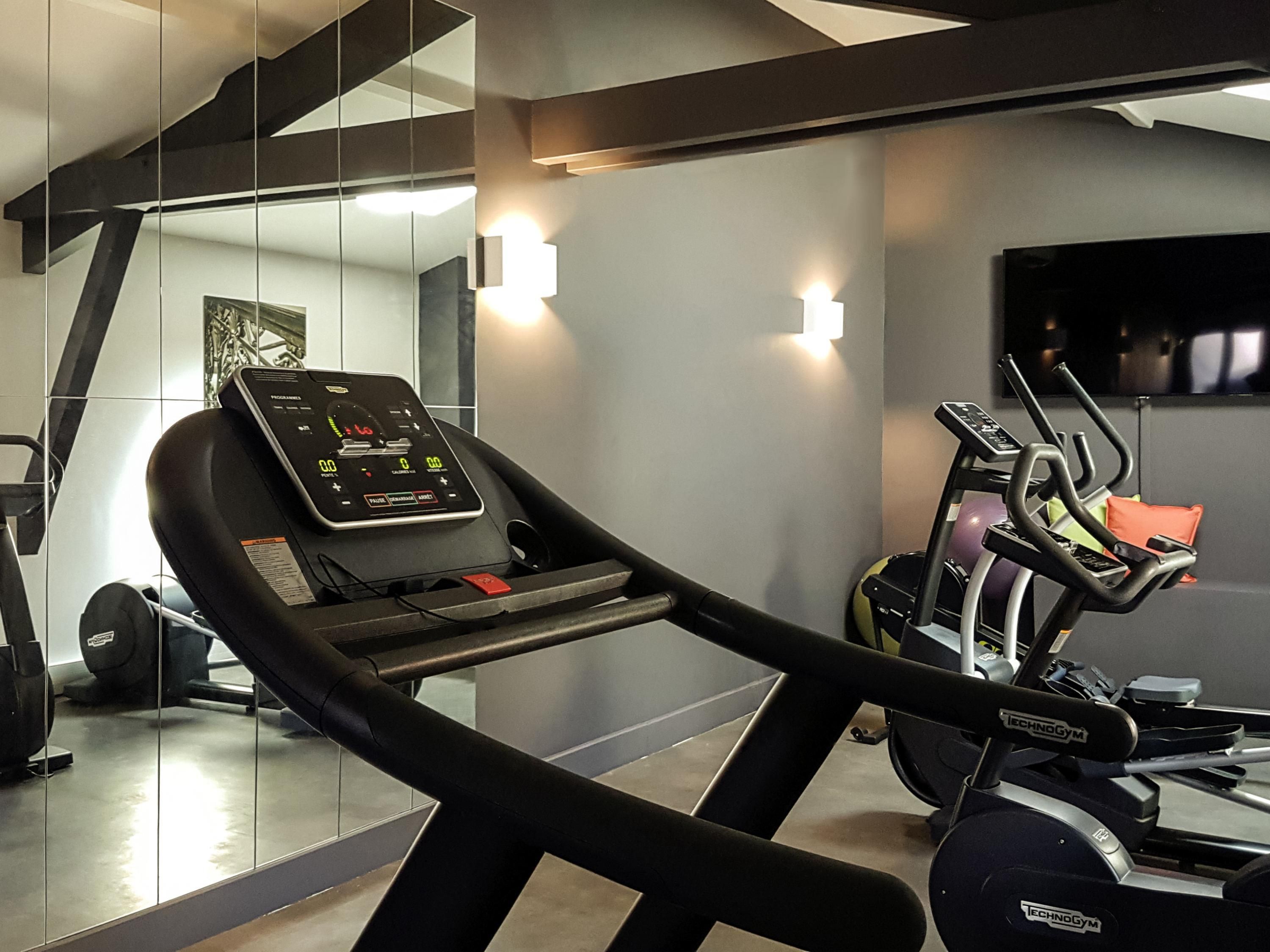 Une salle de sport moderne équipée de tapis de course, d’elliptiques et de vélos d’appartement.