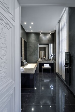 A modern bathroom with a large bathtub, a vanity with a mirror, and a shower area. - La Cour des Consuls Hotel & Spa Toulouse - MGallery Collection (Toulouse)