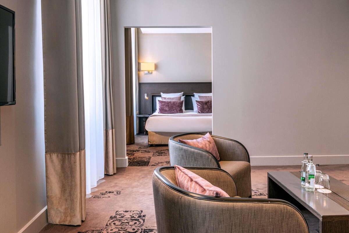 Una habitación de hotel con cama, zona de estar con mesa y televisor.
