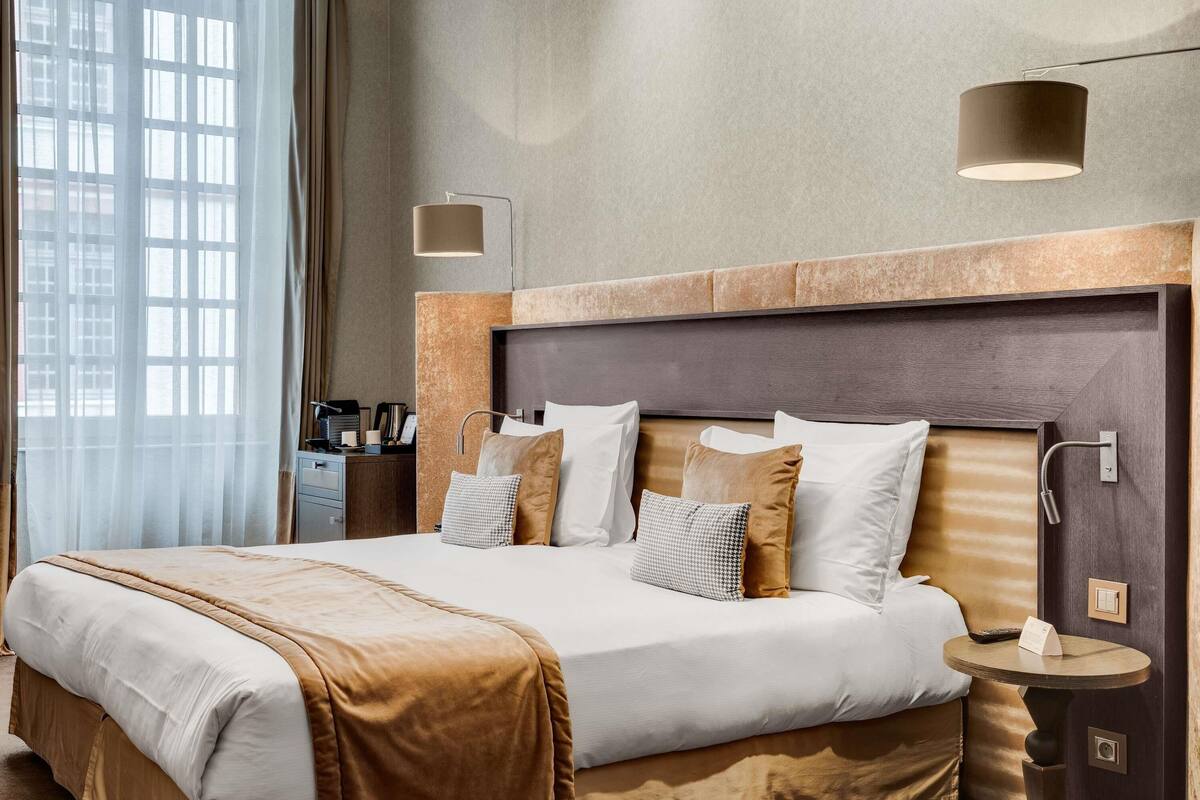 Ein Hotelzimmer mit einem großen Bett, einem Nachttisch, einem runden Tisch und einem Kopfteil.