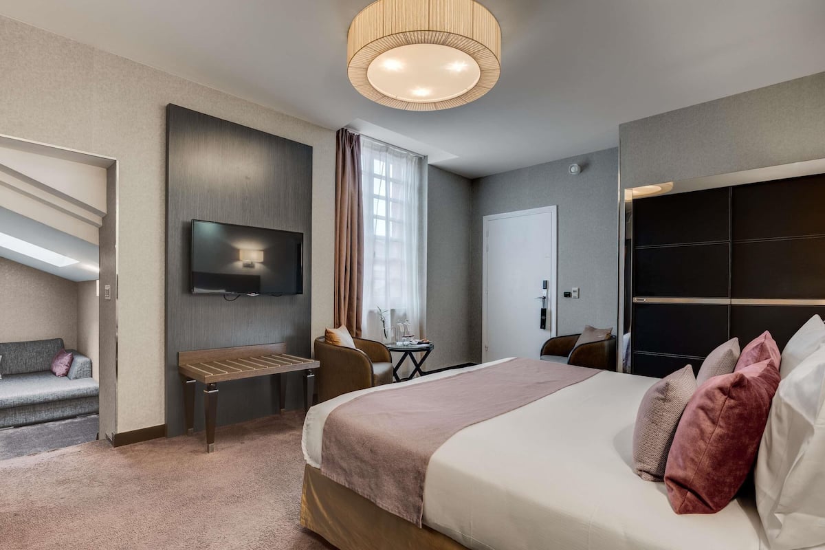 Ein modernes Hotelzimmer mit einem großen Bett, einem Flachbildfernseher, einem Schreibtisch und einer Sitzecke.