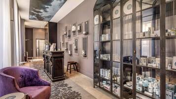 A hotel lobby with a purple armchair, a large glass display case with products, and a ceiling mural.