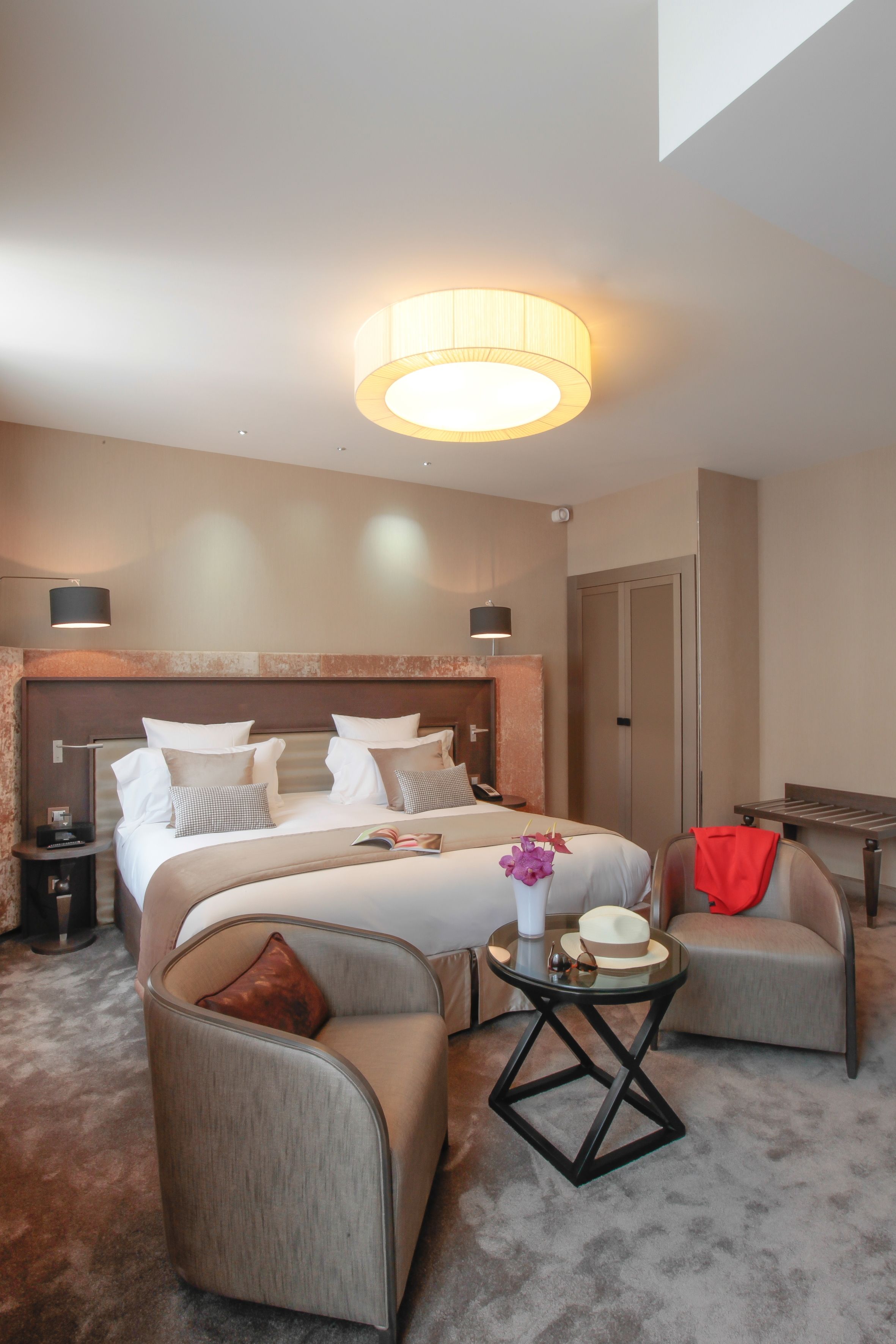 A hotel room with a large bed, two bedside tables, a sofa, a small round table, and a lamp.