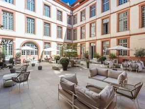 A spacious courtyard with outdoor seating, potted plants, and a central open area.