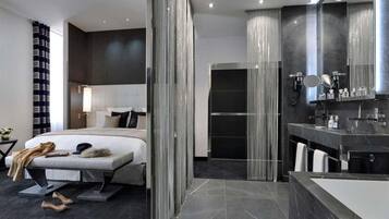 A modern hotel room with a large bed, a separate bathroom, and a large mirror.