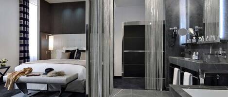 A modern hotel room with a large bed, a separate bathroom, and a large mirror.
