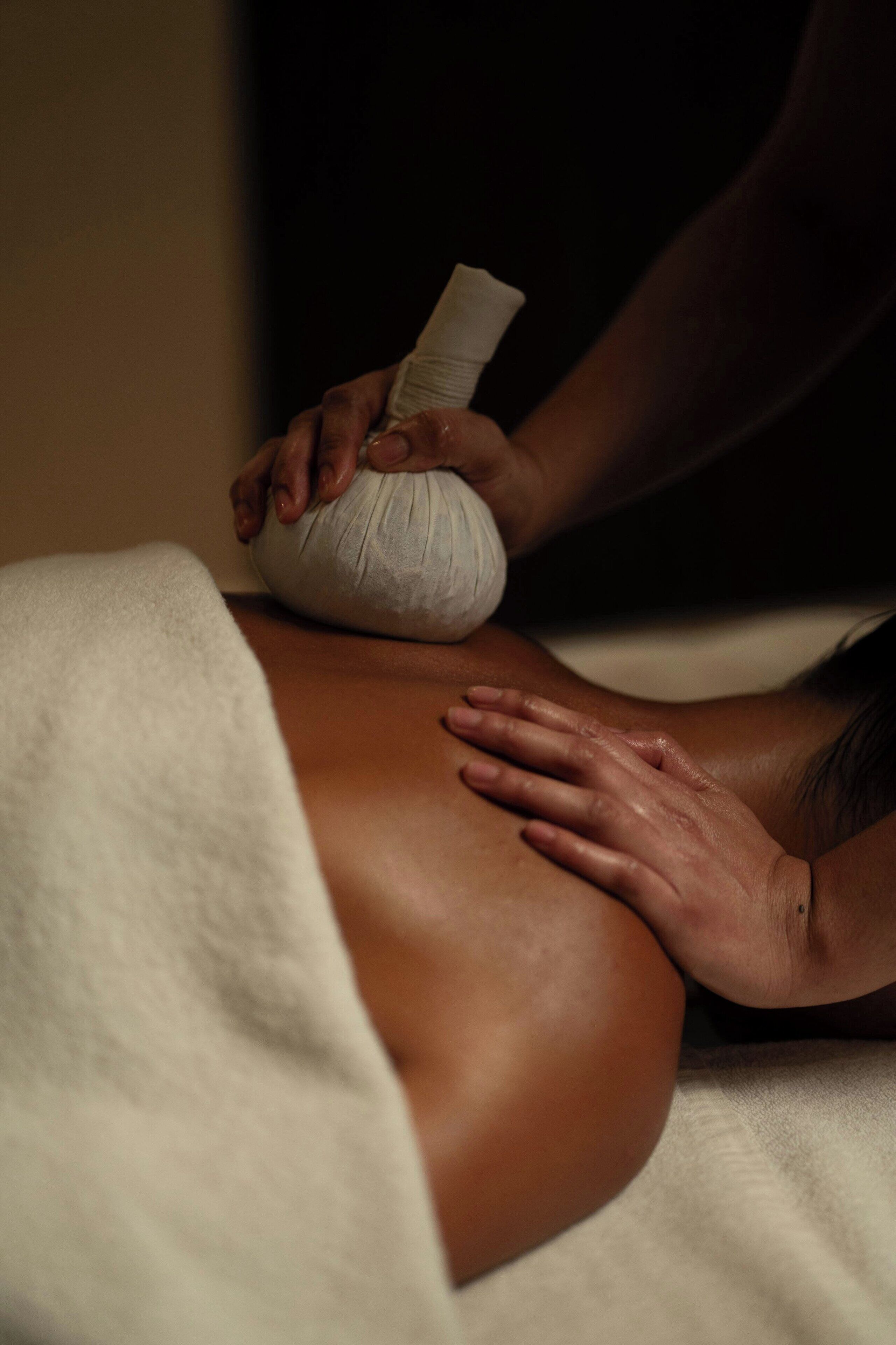 A massage therapy session with a focus on the therapist's hands applying pressure to a client's back.