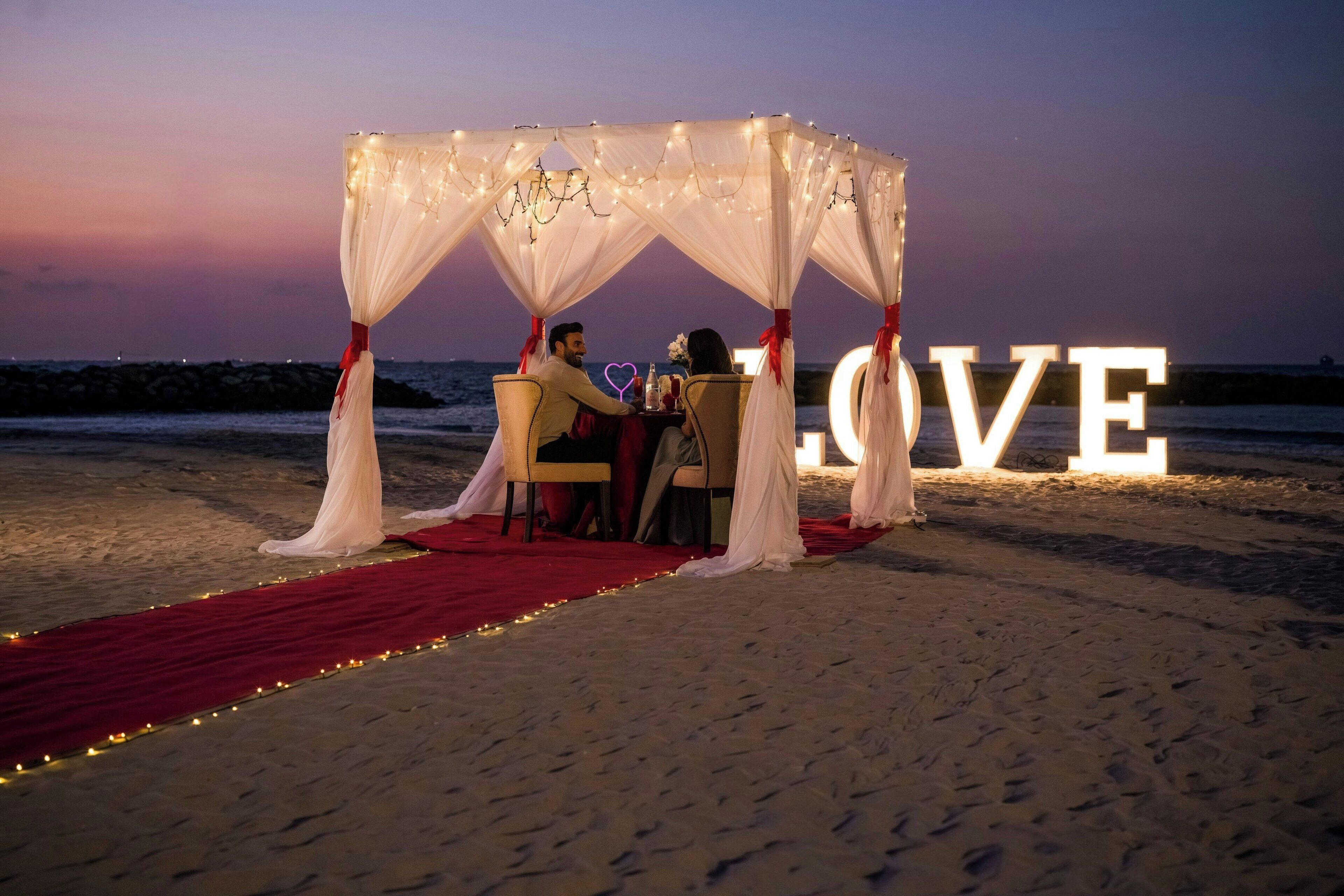 A beach wedding setup with a canopy, a red carpet, and a 'LOVE' sign.