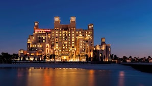 Een groot, meerhoog hotel met een opvallende toren en meerdere balkons, gelegen aan een water.