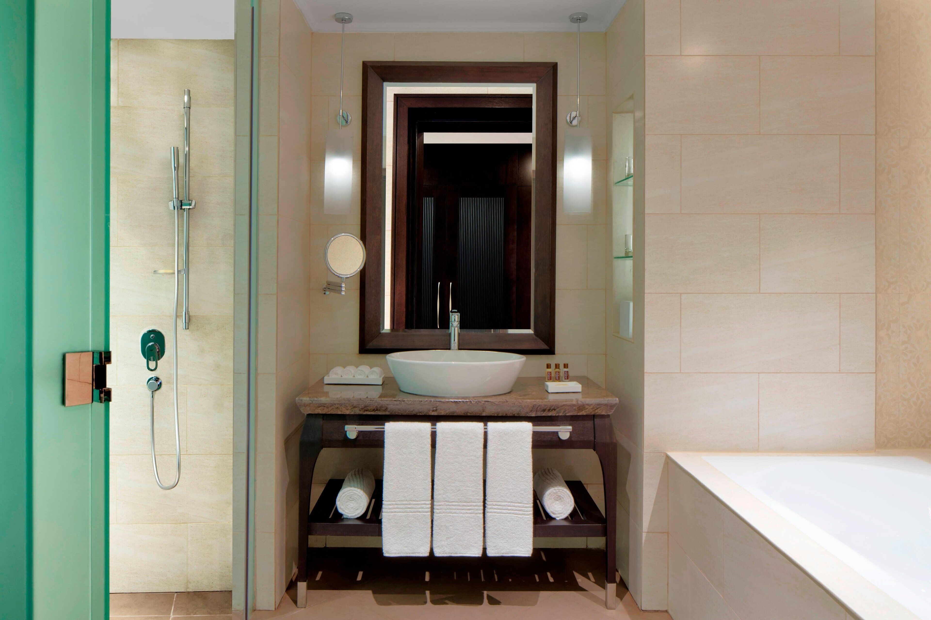A modern bathroom with a large bathtub, a sink with a mirror above it, and a shower area.