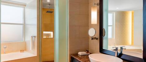 Une salle de bain moderne dotée d’une grande baignoire, d’une douche séparée, d’un meuble-lavabo avec un grand miroir et d’un évier.