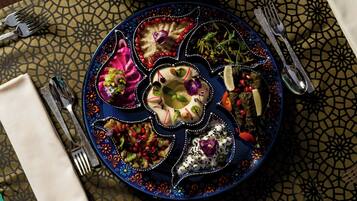 A table with a decorative plate of food, a napkin, and cutlery.