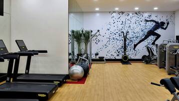 Uma academia com esteiras, bolas de exercício e aparelhos de musculação.