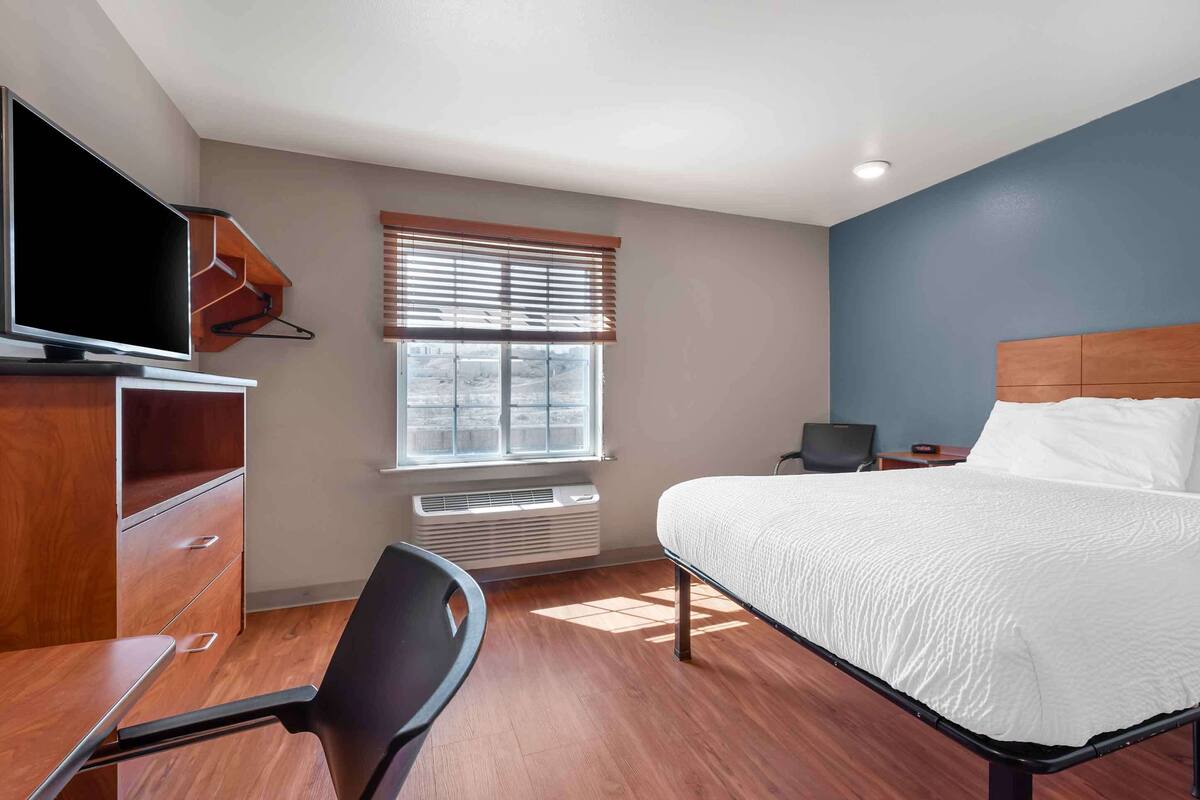 A bedroom with a bed, a TV, a desk, and a chair.