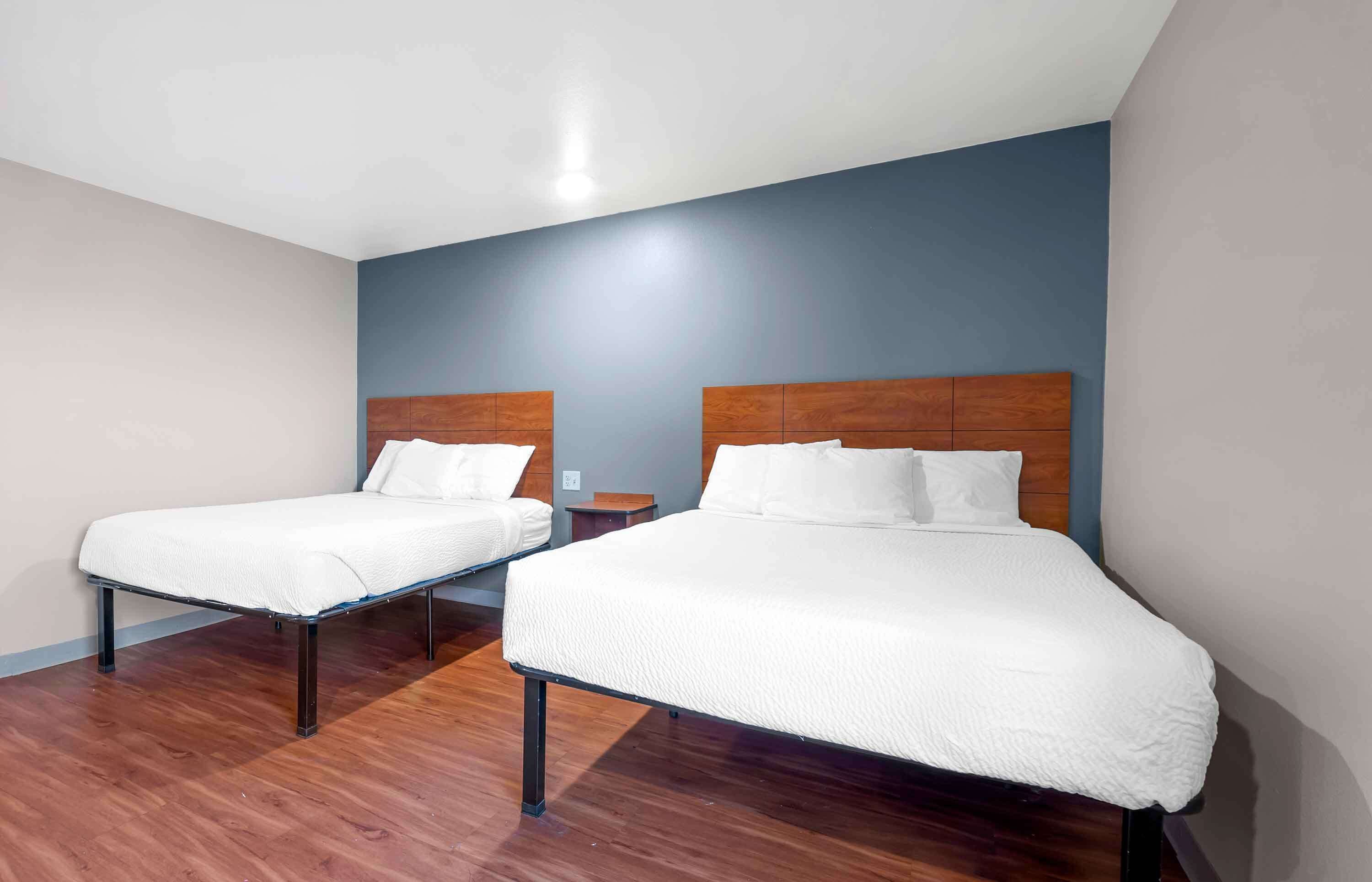 A hotel room with two single beds, wooden headboards, and a wooden floor.
