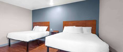 A hotel room with two single beds, wooden headboards, and a wooden floor.