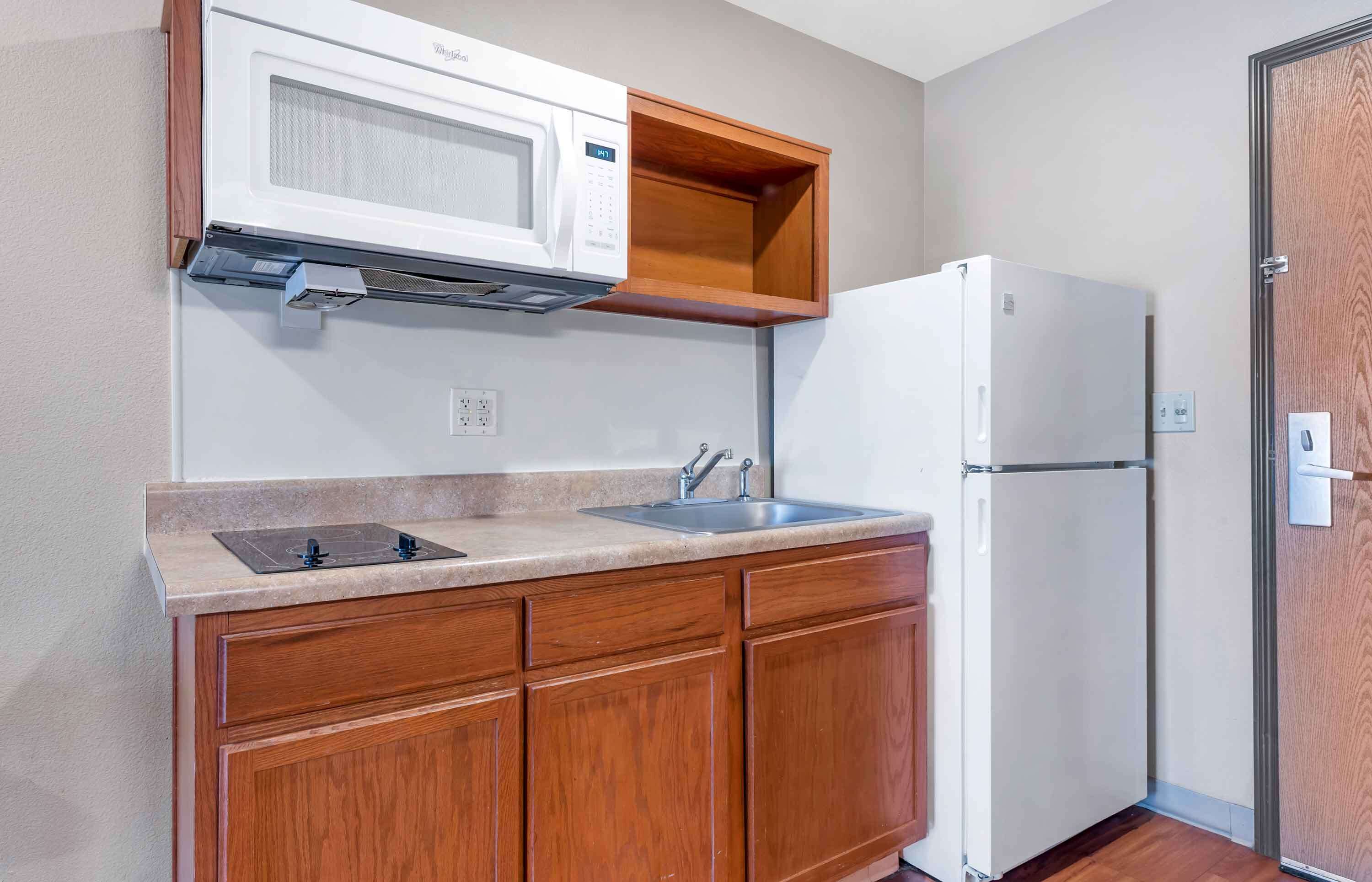 Cocina compacta con microondas, lavabo y refrigerador.