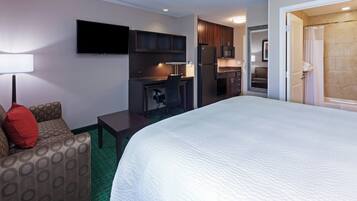 A hotel room with a bed, a desk, a chair, a TV, a microwave, and a shower.