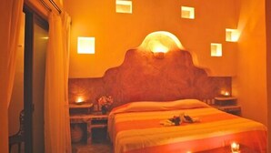 Una habitación de hotel con una cama grande, una mesita de noche, una lámpara y un aplique de pared.