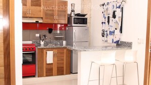 Une cuisine moderne avec des meubles en bois, un four rouge, des appareils en acier inoxydable et un coin bar avec des tabourets blancs.