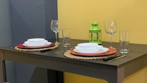 Une table à manger dressée avec des assiettes, des bols, des couverts, des verres et une lanterne verte.