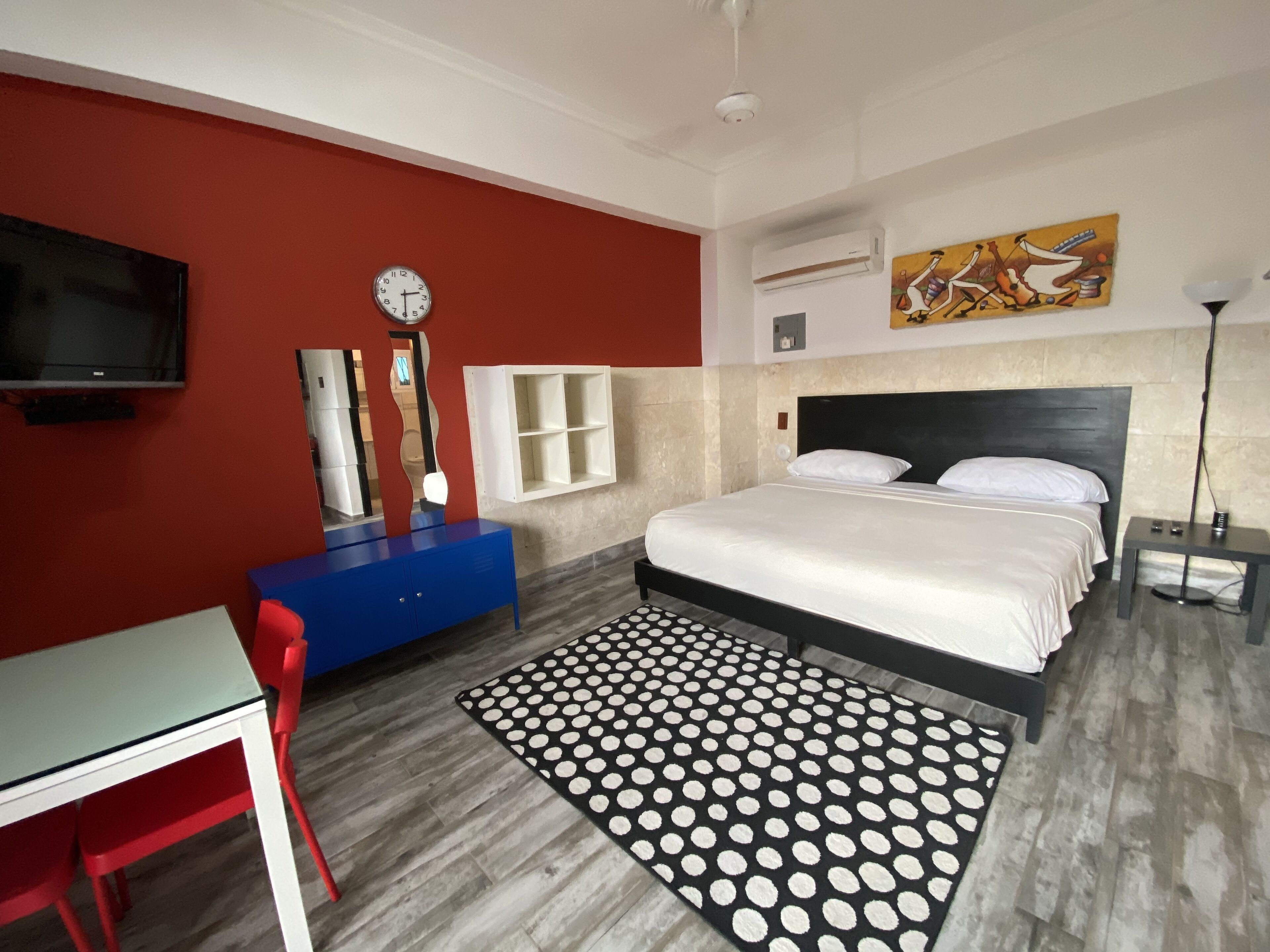 Un dormitorio con una cama, un escritorio, una silla, un reloj y un cuadro en la pared.
