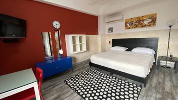 Un dormitorio con una cama, un escritorio, una silla, un reloj y un cuadro en la pared.