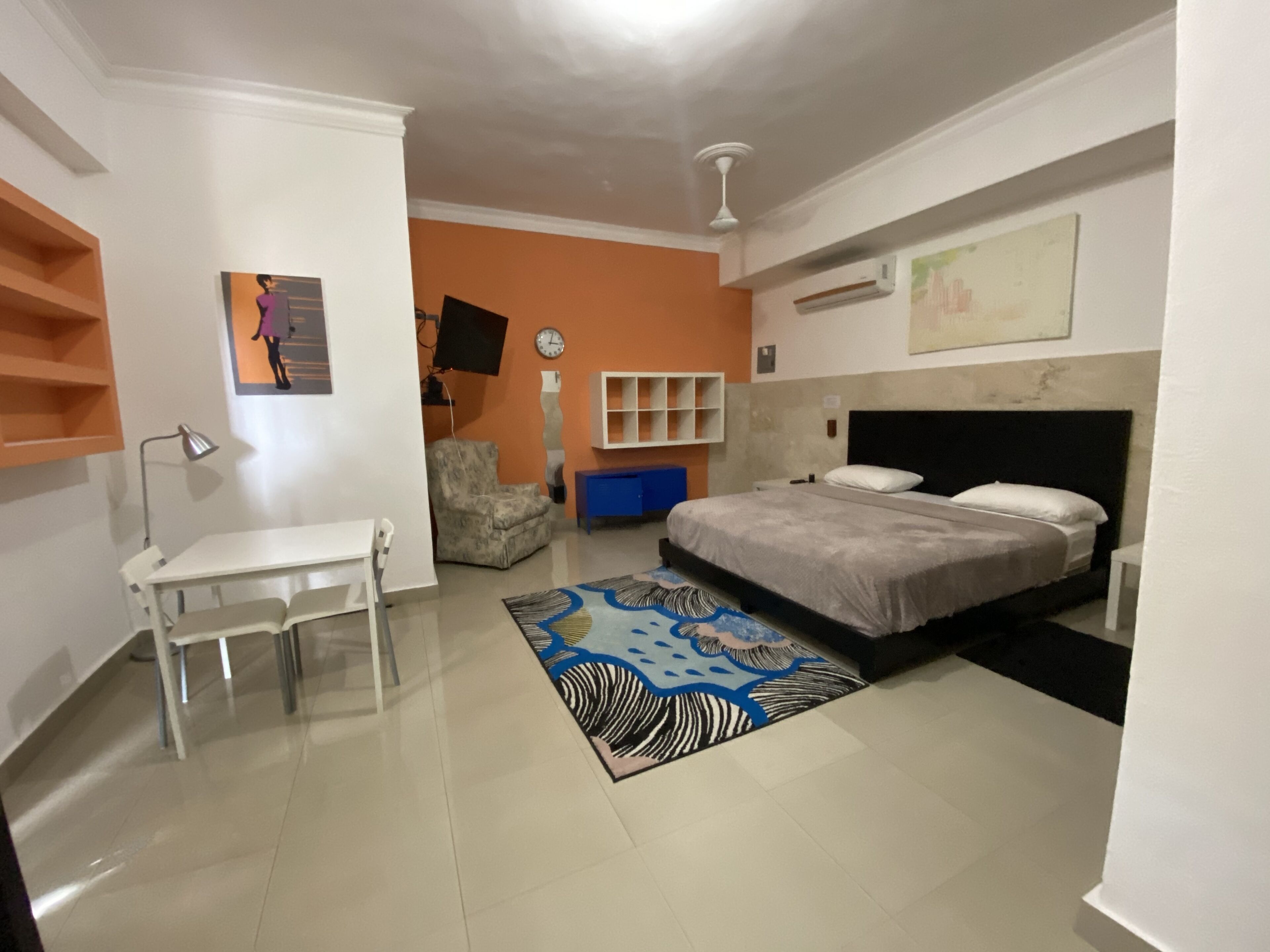 A bedroom with a bed, a chair, a desk, and a TV.