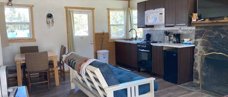 A compact living space with a kitchenette, a bed, a dining area, and a fireplace.