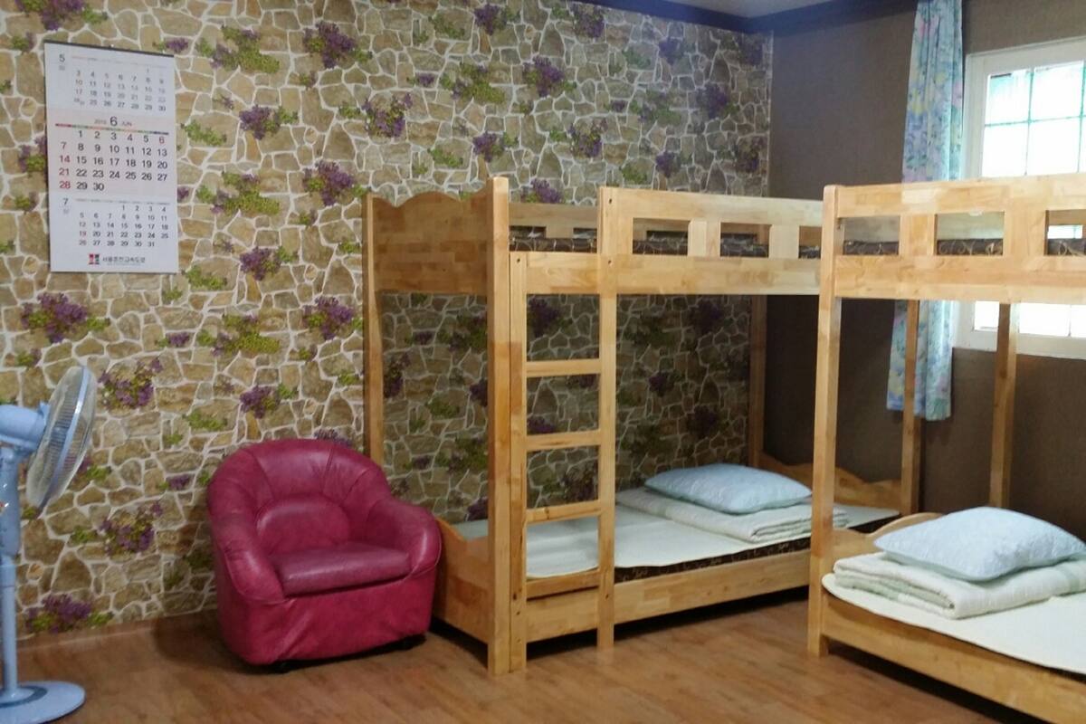 Una habitació amb llits superposats, una cadira vermella i un calendari a la paret.