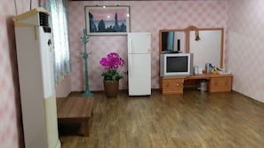 A room with a wooden floor, a refrigerator, a white cabinet, a television, and a potted plant. - Seorak Dongchun Youthtel - Hostel (Sokcho)
