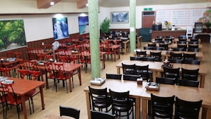 Um restaurante com várias mesas e cadeiras, algumas com dispositivos eletrónicos.