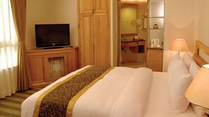 A hotel room with a bed, a television on a wooden cabinet, a bathroom visible through an open door, and a nightstand with a lamp. - Kai Du Hotel (Taoyuan City)
