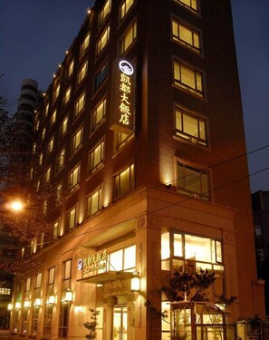 Een hotel met meerdere verdiepingen, verlichte signage en ramen.