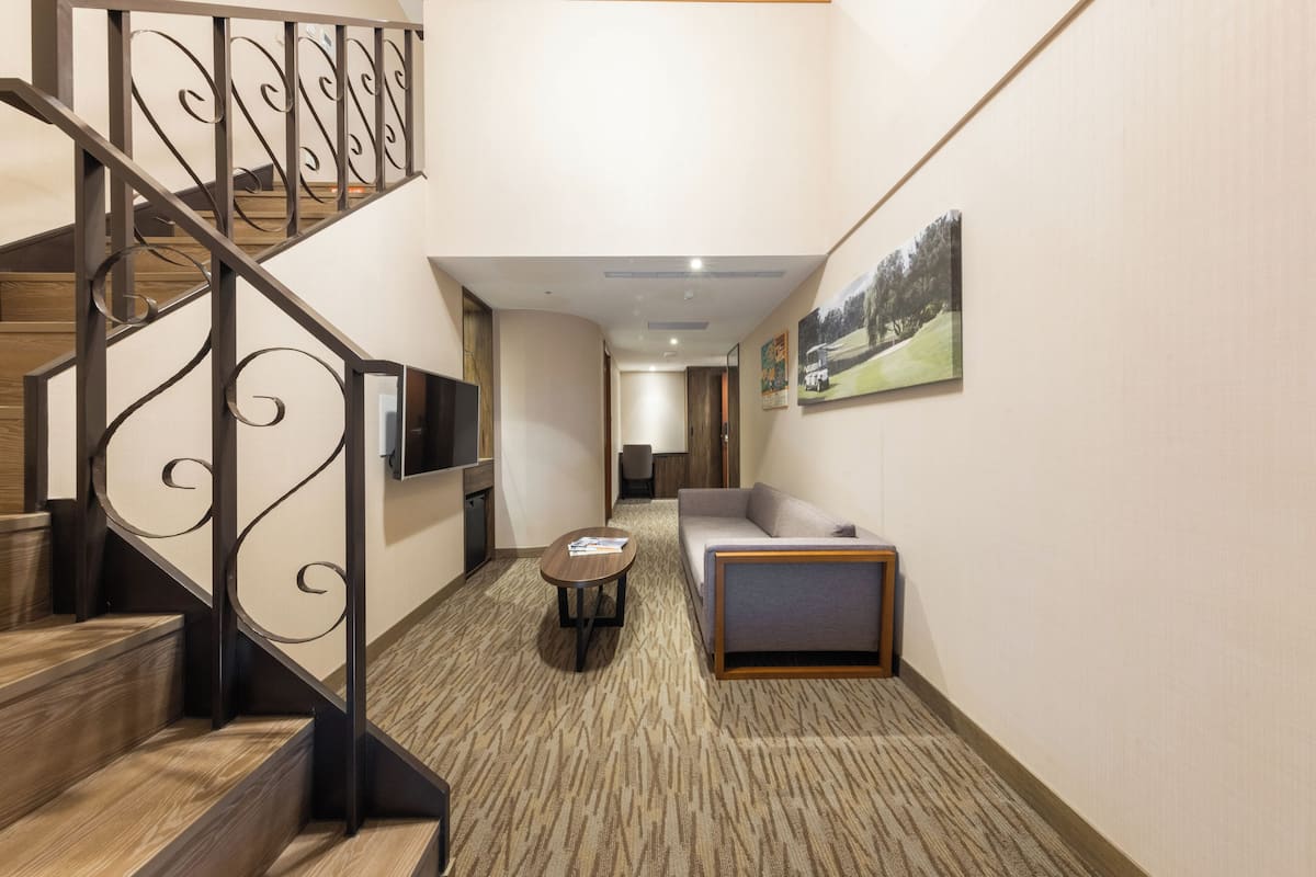 A hotel hallway with a staircase, a sofa, a small table, and a painting on the wall.